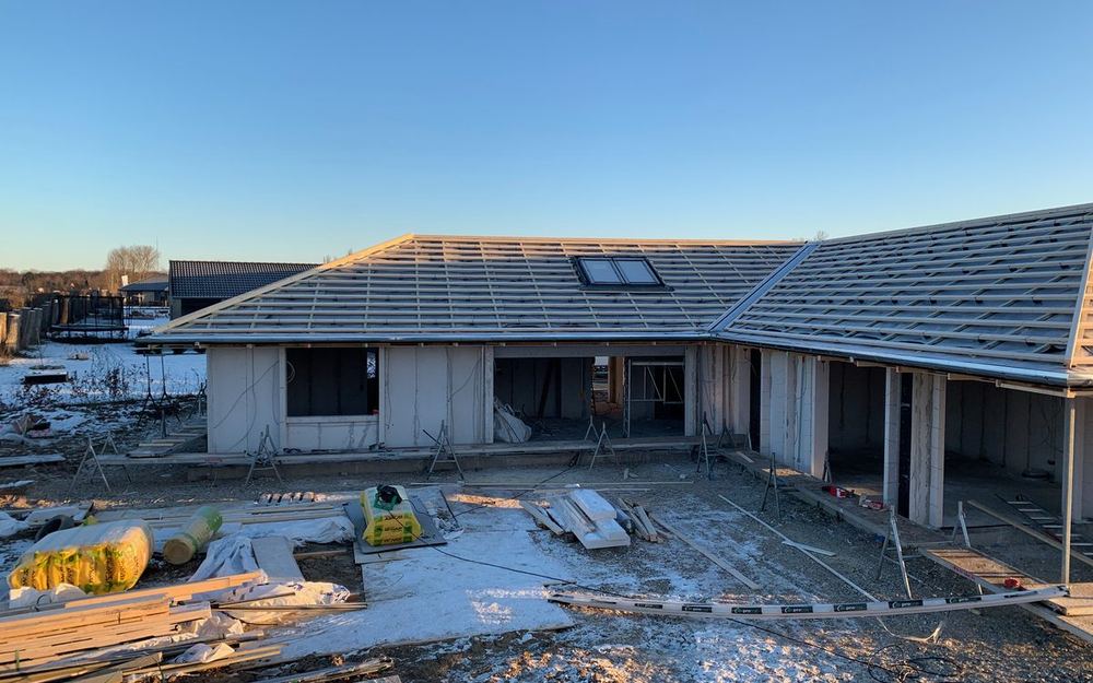 Lukket råhus med tegltag og tomme vindueshuller på en frostklar dag